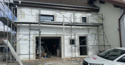 Chantier d'isolation extérieure sur une maison du Sundgau, panneaux isolants posés autour du garage et des fenêtres, échafaudage en place