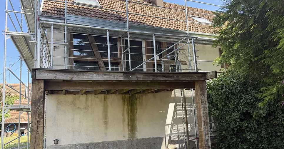 Coulures vertes et mousses sur le mur sous terrasse avant intervention de Peinture Sospera à Riedisheim